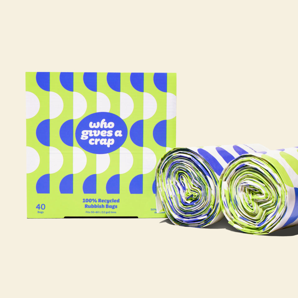 Two rolls and a box of Who Gives a Crap large recycled bin bags with green and blue packaging