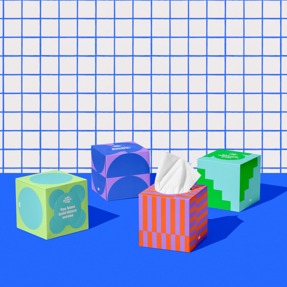 Four boxes of of Who Gives a Crap recycled tissues against blue and while bathroom wall