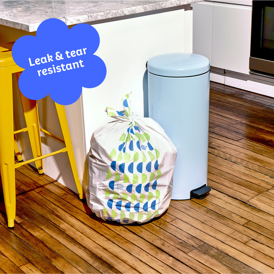 Who Gives a Crap large recycled bin bag sits full next to kitchen bin. Caption in corner reads ‘Leak & tear resistant’.