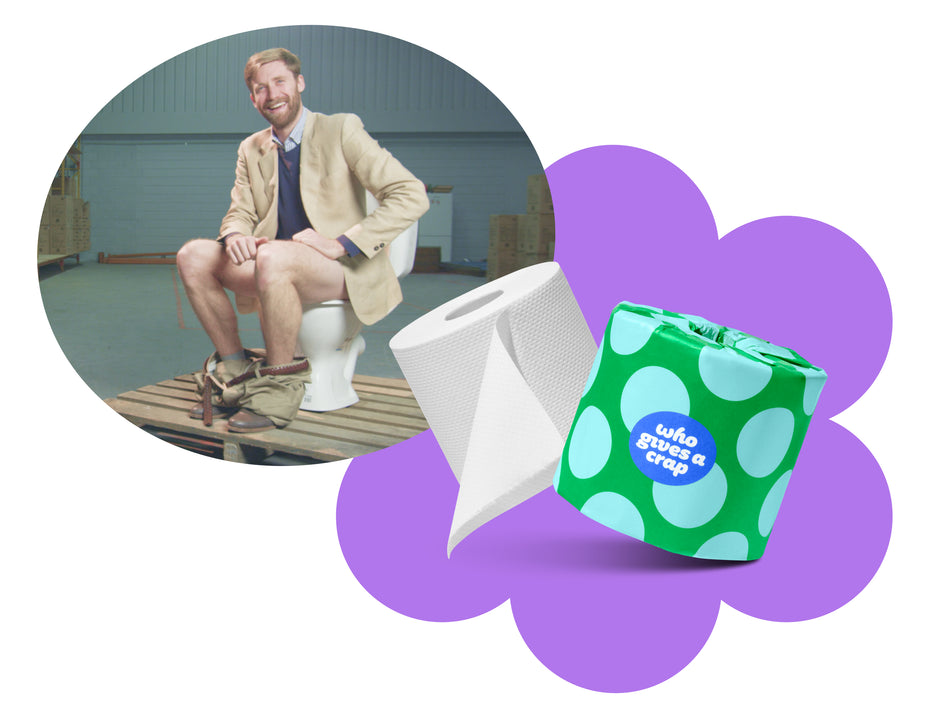 CEO of Who Gives A Crap Toilet Paper Company sitting on a toilet, holding a roll of toilet paper