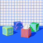Four boxes of of Who Gives a Crap recycled tissues against blue and white bathroom wall