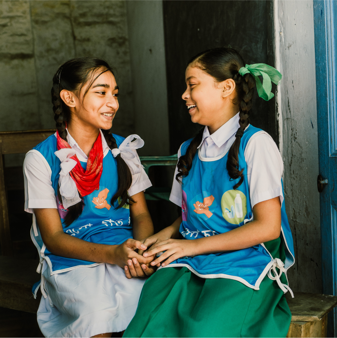 Two girls smiling at each other holding hands