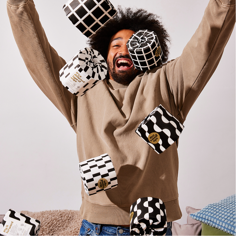 Smiling man throws up rolls of Who Gives a Crap bamboo toilet paper