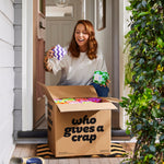 Woman collecting box of Who Gives a Crap toilet paper from front porch of home smiles as she opens box