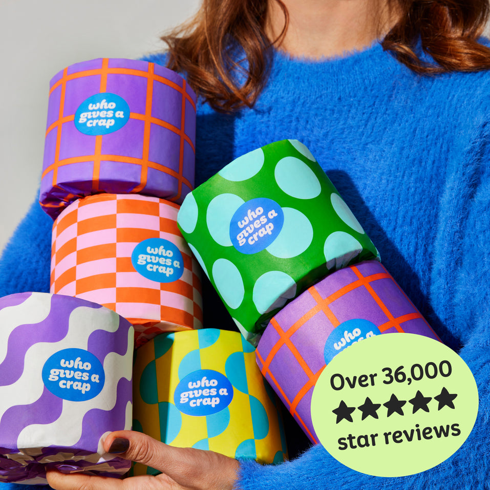 Woman holds handful of colourful Who Gives a Crap recycled toilet paper rolls