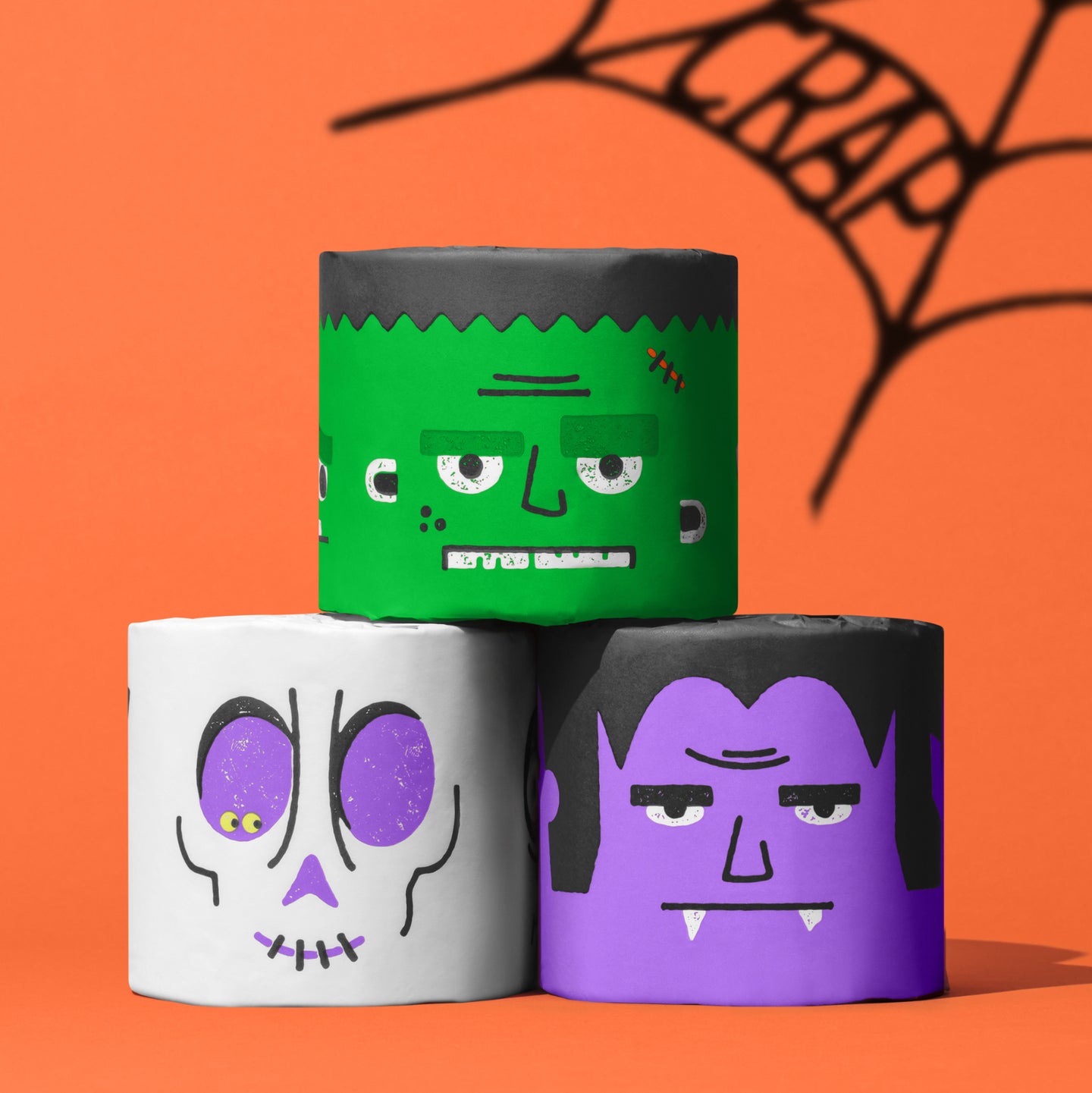 Spooky Edition toilet paper rolls featuring Frankenstein, Dracula and skull designs stacked against orange background