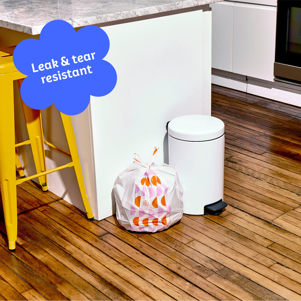 Who Gives a Crap small recycled bin bag sits full next to kitchen bin. Caption in corner reads ‘Leak & tear resistant’.