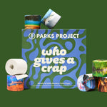Who Gives A Crap x Parks Project 48-roll box surrounded by national-park-design rolls, on a forest-green background.