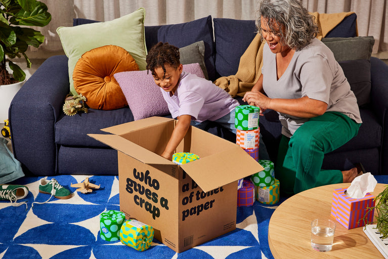 Family unboxing a delivery of Who Gives a Crap recycled toilet paper